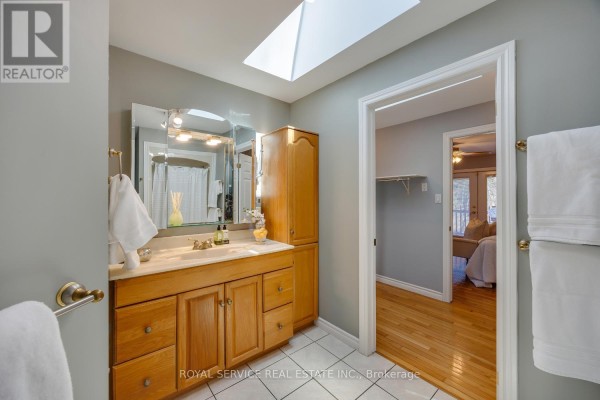 Bathroom with skylight, double vanity, wood cabinets, and bedroom view - 2311 Division Street N Hamilton Township