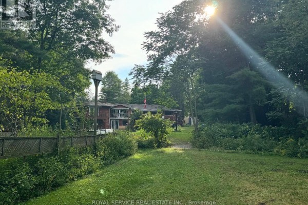 Two-story house with balcony, surrounded by trees, wooden fence, and birdhouse - 2311 Division Street N Hamilton Township