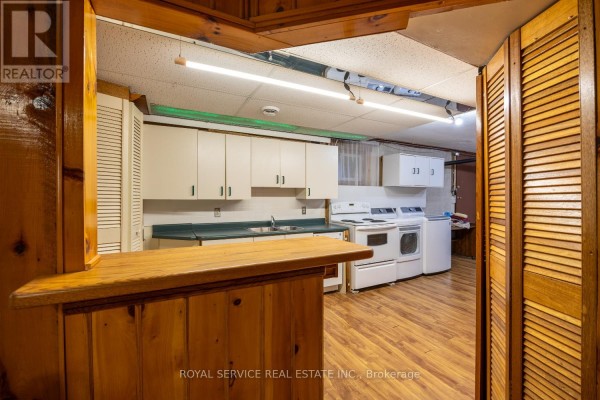 Kitchen with wooden bar, white cabinets, stove, washer, dryer, and louvered doors - 2311 Division Street N Hamilton Township