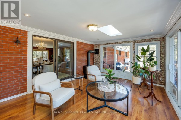 Sunroom with brick wall, wood floors, skylight, wood stove, and plants - 2311 Division Street N Hamilton Township