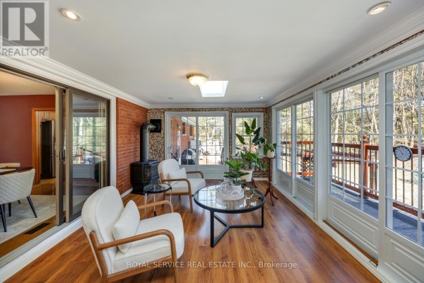 Sunroom with wood-burning stove, accent chairs, glass coffee table, and large windows - 2311 Division Street N Hamilton Township