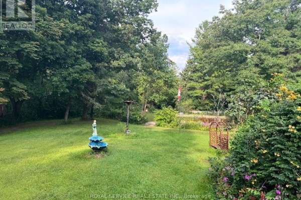 Yard with fountain, trees, garden archway, and Canadian flag - 2311 Division Street N Hamilton Township
