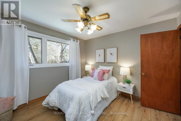 Bedroom with white bedding, floral art, and wood floors - 2311 Division Street N Hamilton Township