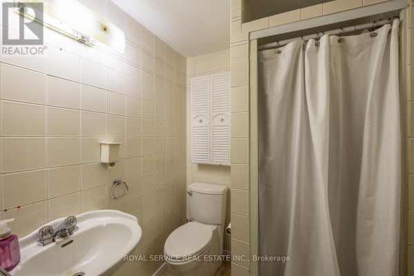 Bathroom with tiled walls, pedestal sink, toilet, and shower curtain - 2311 Division Street N Hamilton Township