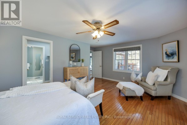 Bedroom with hardwood floors, ceiling fan, armchair, and ensuite access - 2311 Division Street N Hamilton Township