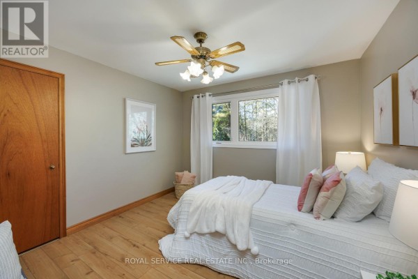 Bedroom with wooden door, ceiling fan, window, and bed with decorative pillows - 2311 Division Street N Hamilton Township
