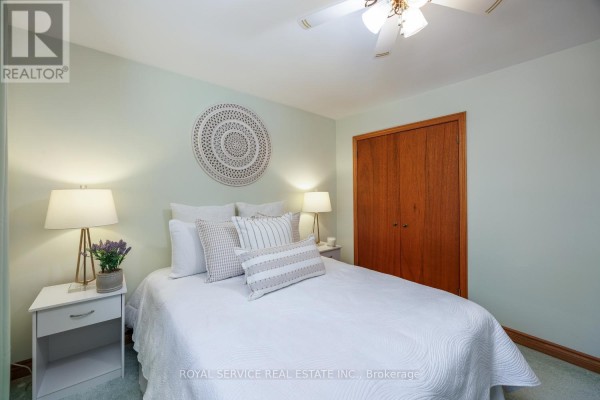 Bedroom with white quilted bed, decorative wall art, wooden closet, and nightstands - 2311 Division Street N Hamilton Township