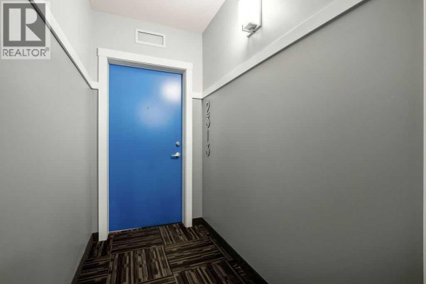 Apartment door 2513 painted bright blue, set against a grey hallway with patterned carpet. - 2313, 19489 Main Street Se, Calgary
