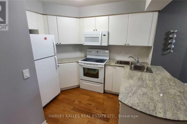 Kitchen area with white appliances, granite countertops, sink, and hardwood floor. - 2313 - 763 Bay Street, Toronto