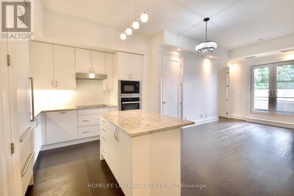 Modern kitchen with white cabinetry, granite island, and dark wood flooring. - 232 - 20 Fred Varley Drive, Markham