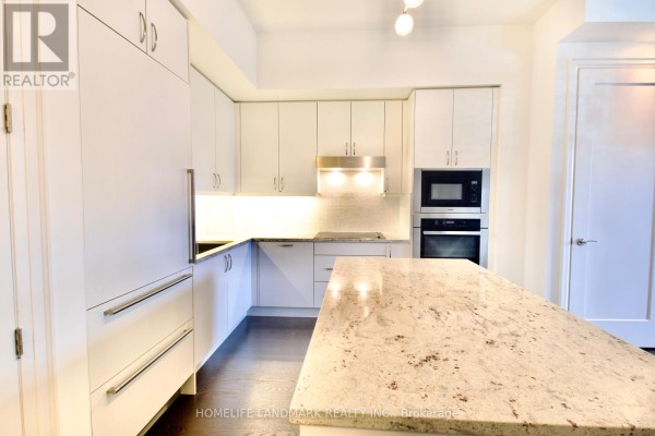 View of kitchen from an angle showing white cabinetry and stainless steel appliances. - 232 - 20 Fred Varley Drive, Markham