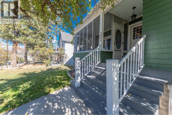 Exterior view of the front porch with gray steps and white railings leading to the entrance. - 232 10th Avenue S, Cranbrook