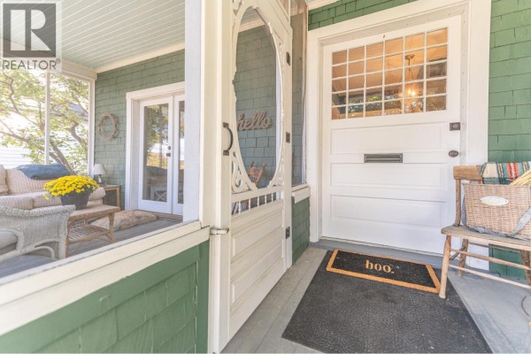 View from the porch of the front door and screened-in area with seating. - 232 10th Avenue S, Cranbrook