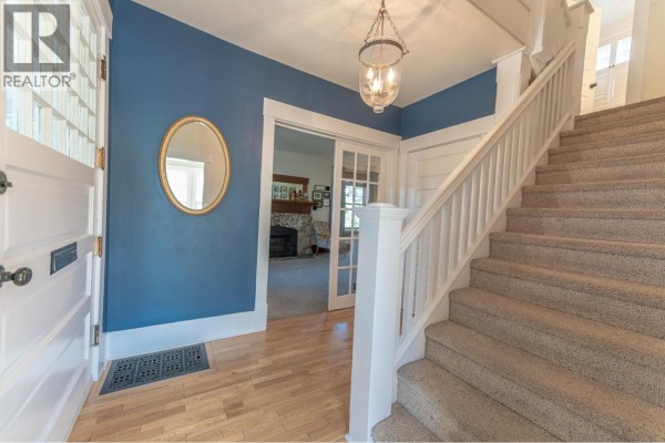 Interior hallway with blue walls, a mirrored oval wall hanging, and a carpeted staircase. - 232 10th Avenue S, Cranbrook
