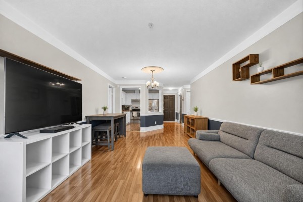 Living room with fireplace, light beige sofa, cream armchair, and two large windows. - 232 8068 120a Street, Surrey