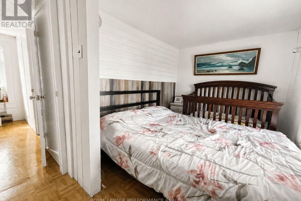 Bedroom with floral duvet, wooden headboard, and landscape painting - 232 Regent Street Hawkesbury