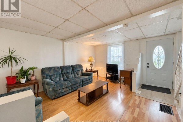 Living room and entryway with a teal floral sofa, television, and a white front door with oval glass. - 232 Regent Street, Hawkesbury
