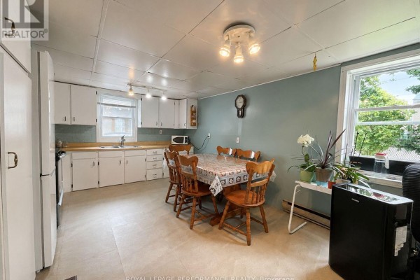 Dining area with a table set for six, a china cabinet, and white refrigerators on the right. - 232 Regent Street, Hawkesbury