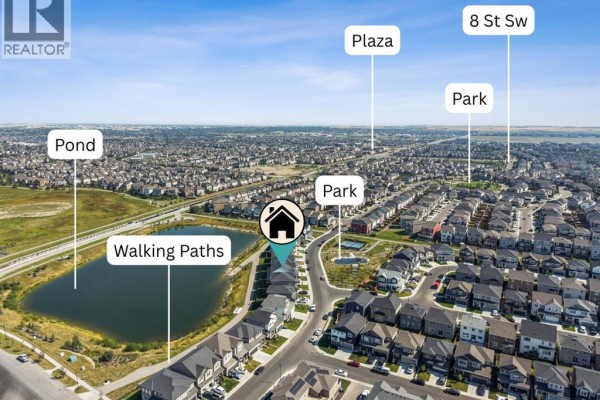 Aerial view of a residential neighborhood showing houses, walking paths, parks, and a pond. - 232 Windrow Link Sw, Airdrie