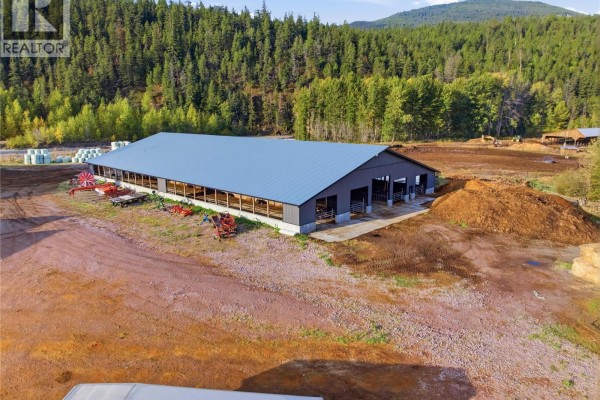 Large grey barn with open sides, concrete foundation, and farm equipment nearby. - 2321 Peterson Road, Merritt