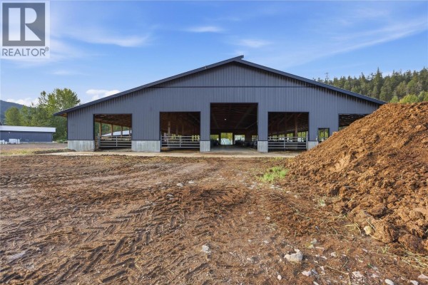 Exterior of a large dark grey barn with three wide openings and a dirt pile. - 2321 Peterson Road, Merritt