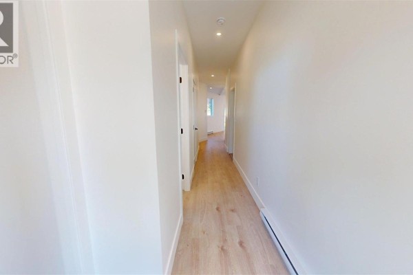 Bright white hallway with light wood laminate flooring and black interior doors. - 2322 Sparrow Lane, Nanaimo
