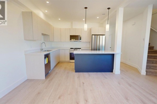 Contemporary kitchen with light wood floors, white countertops, and light wood cabinets. - 2322 Sparrow Lane, Nanaimo