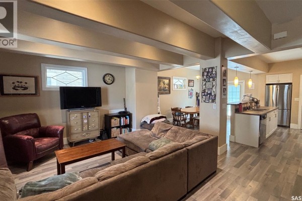 Living room and adjacent dining area with a sectional sofa, armchair, and dining table visible. - 2324 Halifax Street, Regina