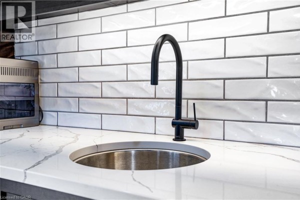 White subway tile backsplash with black grout, quartz countertop, undermount sink, and black faucet - 23247 Beattie Drive Elgin