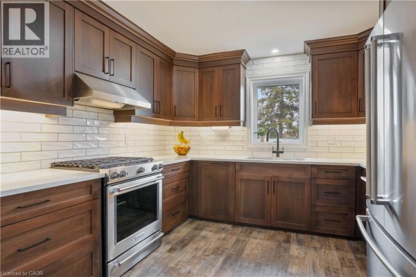 Modern kitchen with dark wood cabinets, stainless steel gas range, and subway tile backsplash - 23247 Beattie Drive Elgin