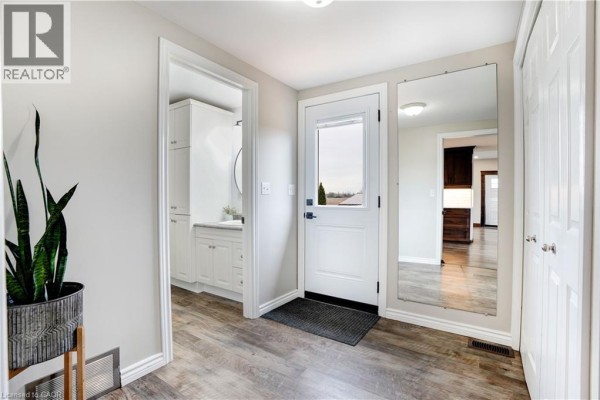 Hallway with front door, full-length mirror, snake plant, and bathroom view - 23247 Beattie Drive Elgin