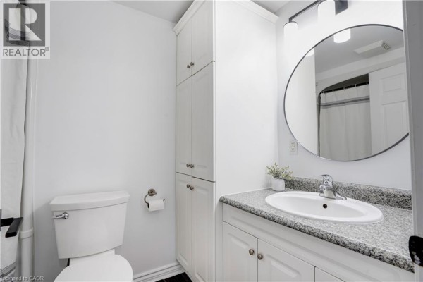 Modern bathroom with white toilet, storage cabinet, granite vanity, oval sink, and round mirror - 23247 Beattie Drive Elgin