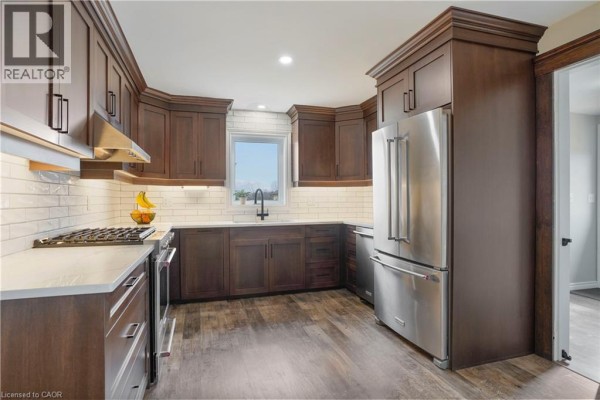 Modern kitchen with dark wood cabinets, stainless steel appliances, and subway tile backsplash - 23247 Beattie Drive Elgin