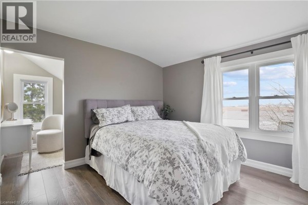 Bedroom with tufted headboard, patterned bedding, arched ceiling, and wood floors - 23247 Beattie Drive Elgin