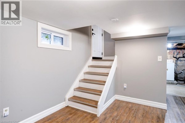 Renovated basement with stairs, window, laundry area, and exposed brick - 23247 Beattie Drive Elgin