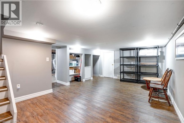 Finished basement with vinyl plank flooring, storage shelves, and staircase - 23247 Beattie Drive Elgin