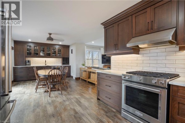 Kitchen with dark wood cabinets, gas range, and dining set - 23247 Beattie Drive Elgin