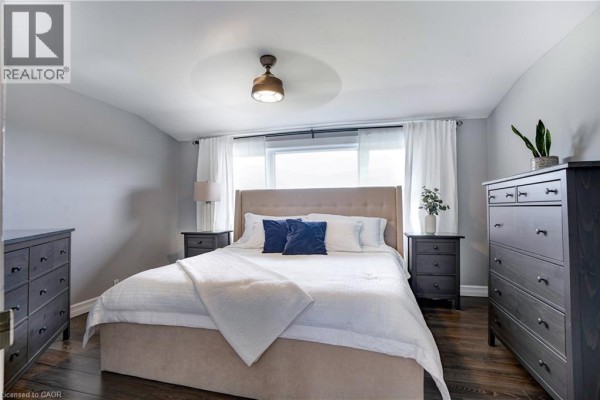 Bedroom with king bed, tufted headboard, dressers, and hardwood floors - 23247 Beattie Drive Elgin
