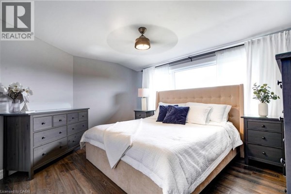 Bedroom with king bed, upholstered headboard, ceiling fan, dressers & hardwood floors - 23247 Beattie Drive Elgin