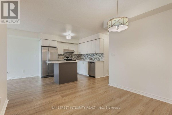View of the open concept kitchen and dining area with light wood laminate flooring. - 2328 - 3888 Duke Of York Boulevard, Mississauga