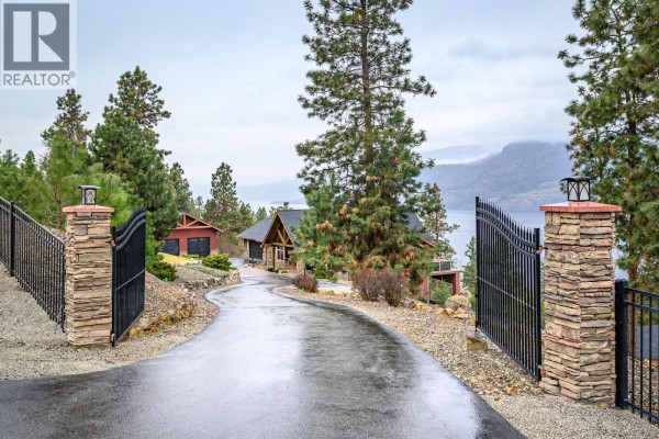 Front view of the house featuring a stone facade, garage, and landscaped driveway. - 2328 Arthur Court, Kelowna