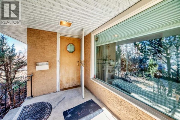 Front entrance with a wooden door, glass window, and covered porch with a mail slot. - 2328 Capitol Hill Crescent Nw, Calgary