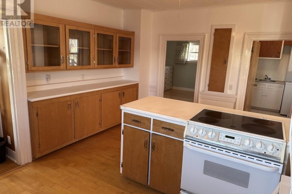 Kitchen with light wood cabinets and a white stove, looking into a bedroom and another doorway. - 2328 Highway 331, West Lahave