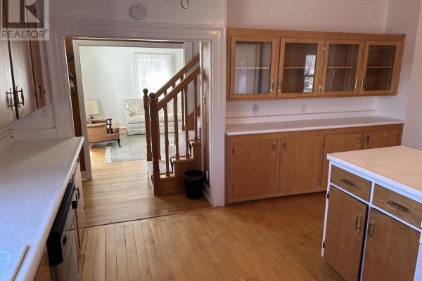 View from the kitchen into a living room with stairs and furniture, showing hardwood floors. - 2328 Highway 331, West Lahave