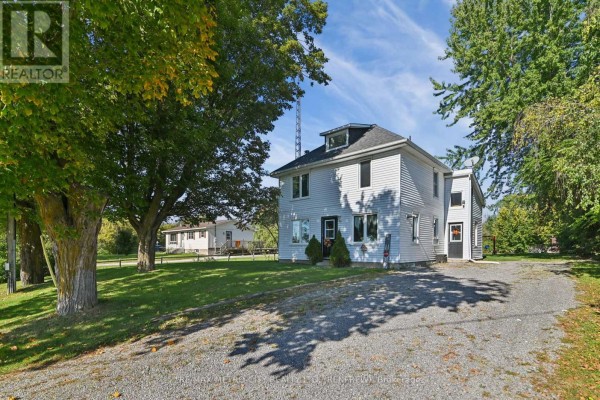 Gravel driveway leads to a white two-story house with trees and lawn. - 2328 Kerr Line, Whitewater Region