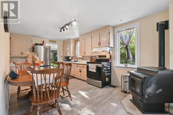 Kitchen and dining area with light wood cabinets, a wood stove, and dining set. - 2328 Kerr Line, Whitewater Region