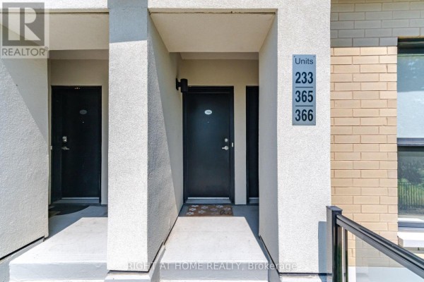 Front entrance to apartment units with grey stairs, black doors, glass railings, and air conditioning units. - 233 - 515 Kingbird Grove, Toronto