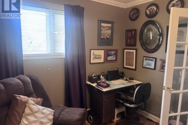 A small desk and chair in a room with purple curtains and framed pictures on the wall. - 233 Elizabeth Drive, Gander