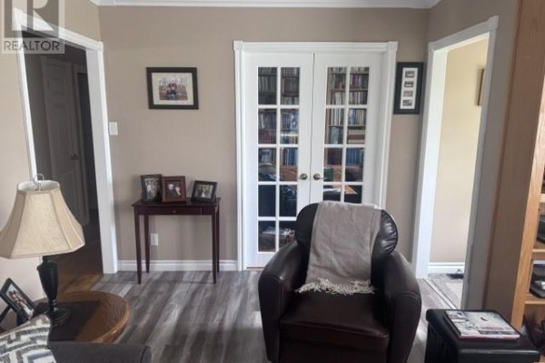 Interior view of a room with a leather armchair, a small side table, and French doors. - 233 Elizabeth Drive, Gander