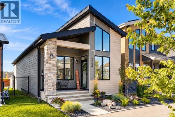 Front facade of the house with stone pillar, covered porch, and large windows. - 233 Haskayne Drive Nw, Calgary